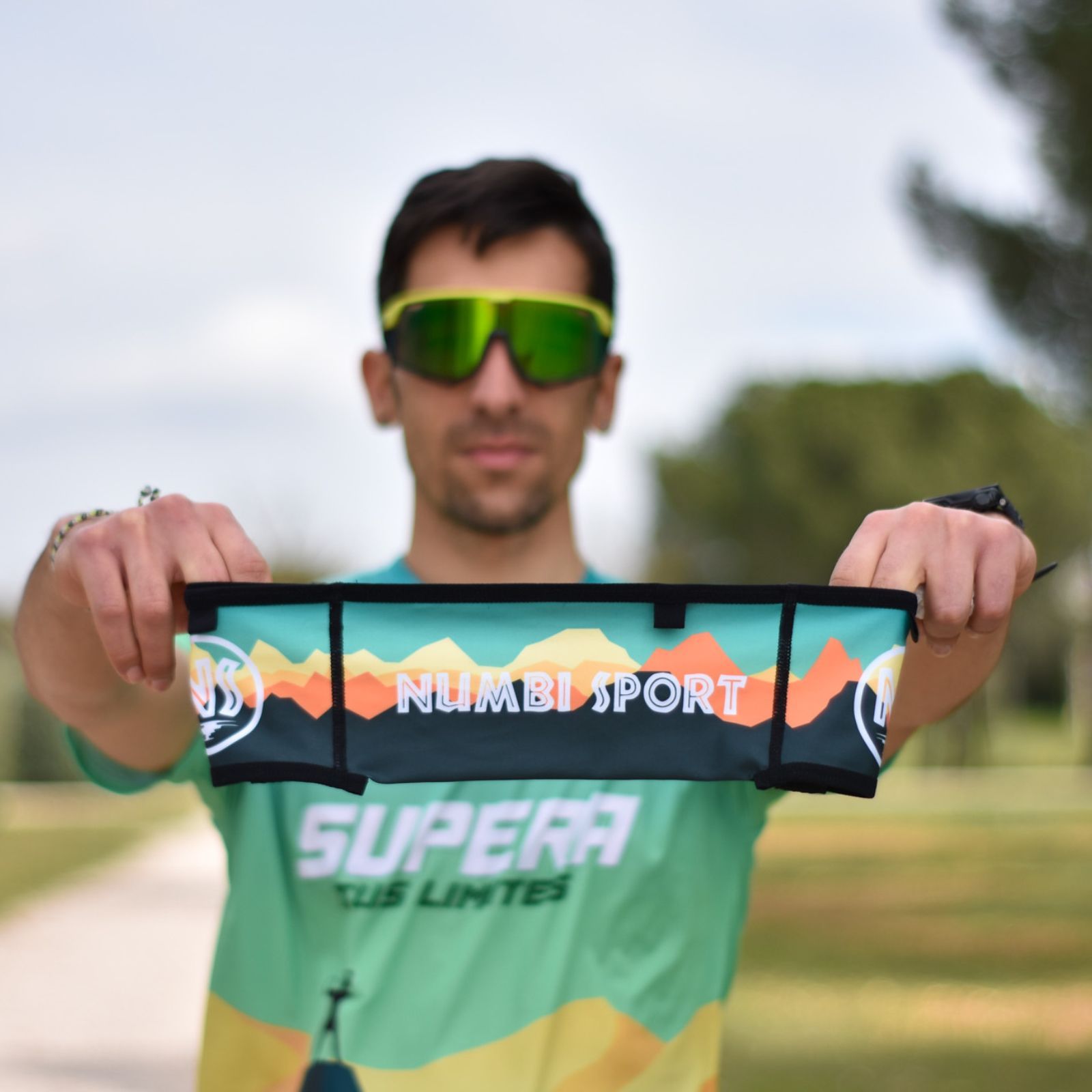 hombre sujetando un cinturón running con montañas en tonos verdes